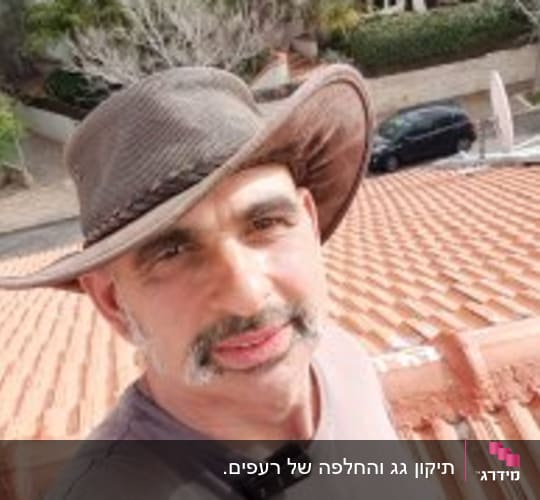 אדם עומד על גג רעפים אדום עם כובע רחב שוליים